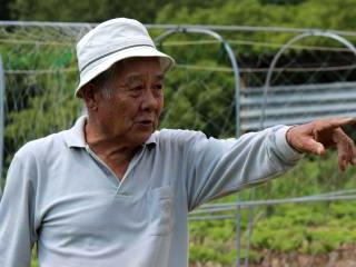 向こうを指さして、説明をする大屋茂夫さん。