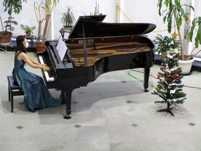 鮮やかなグリーンのドレスとクリスマスツリーが華やかな奏者